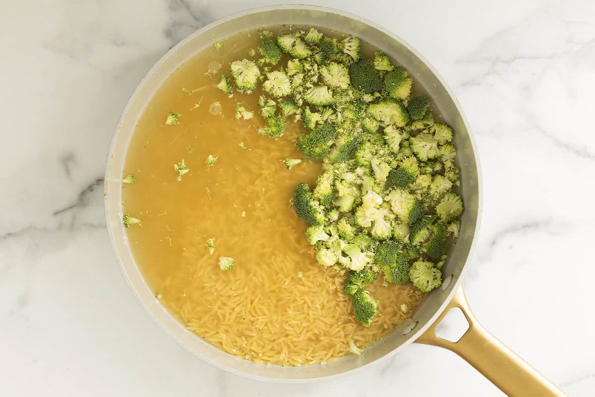 Orzo, broccoli, onion, and broth in a wide skillet.