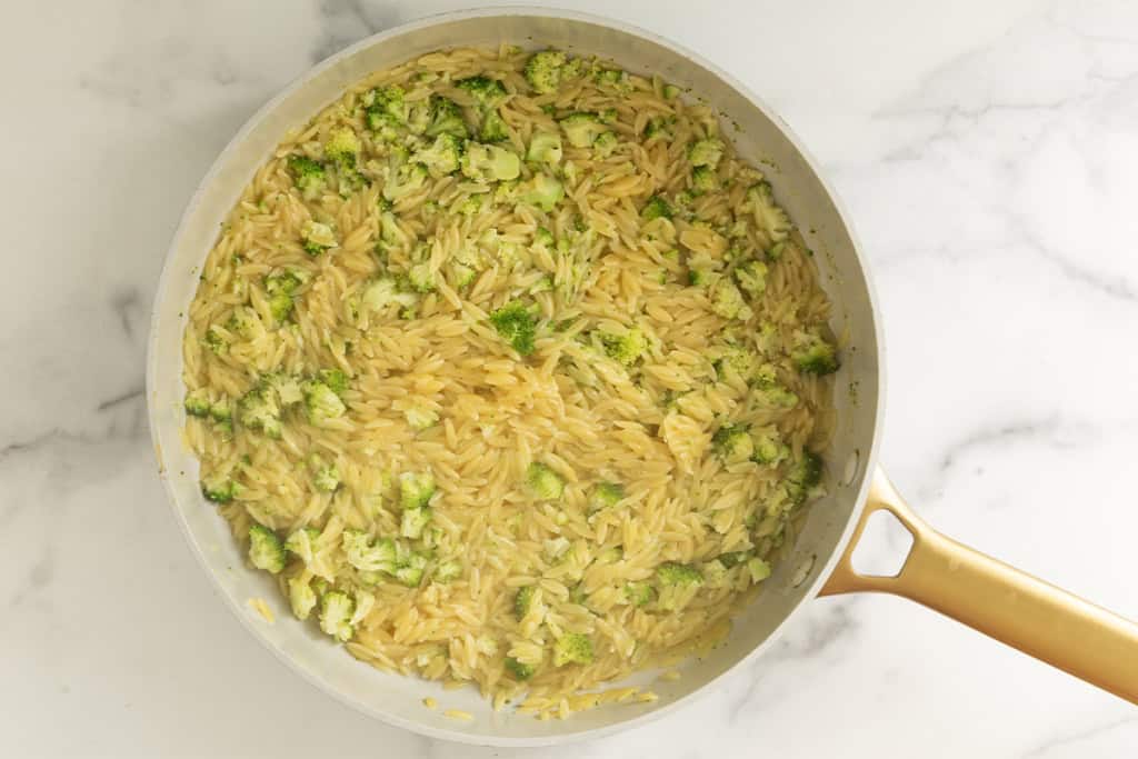 Cooked orzo and broccoli in a wide skillet.
