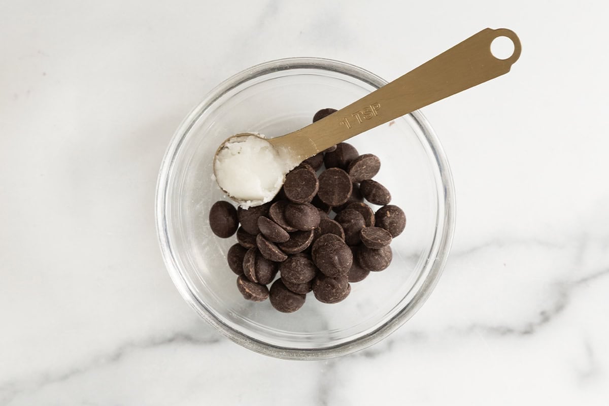 Dark chocolate chips and coconut oil in a glass bowl.