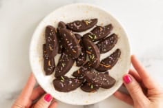 Chocolate covered apple slices with sprinkles on a plate.