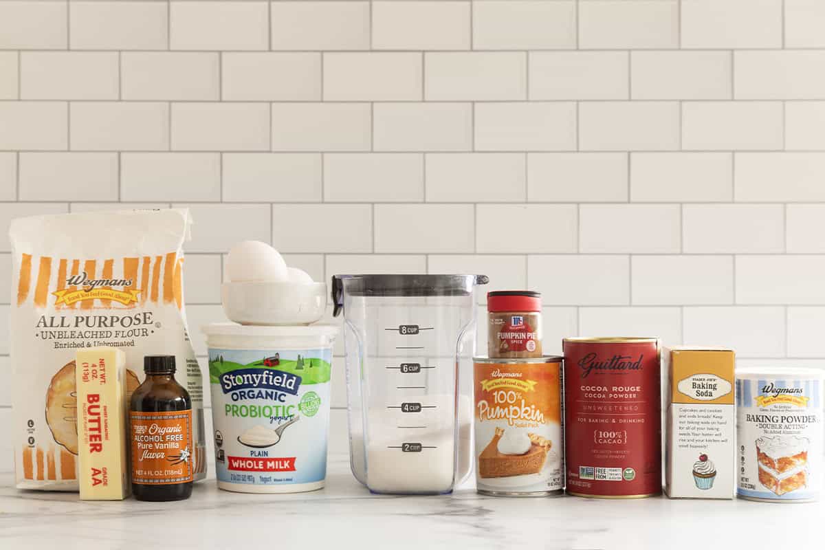 Flour, butter, vanilla, yogurt, eggs, sugar, pumpkin puree, pumpkin pie spice, cocoa powder, baking soda, and baking powder for chocolate pumpkin muffins.