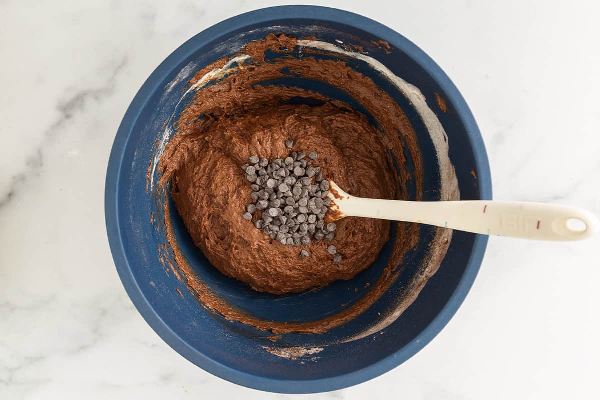 Chocolate pumpkin muffin batter with mini chocolate chips in a blue bowl.