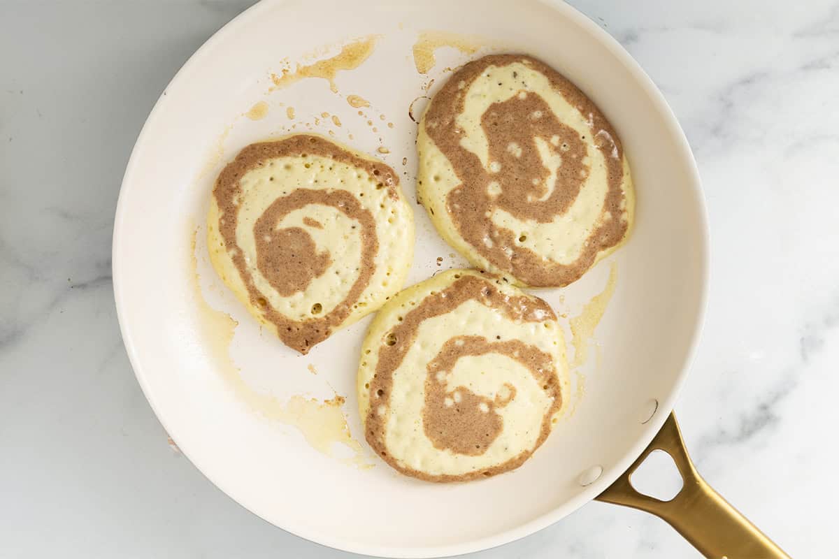 Cinnamon swirl pancakes in pan before flipping.