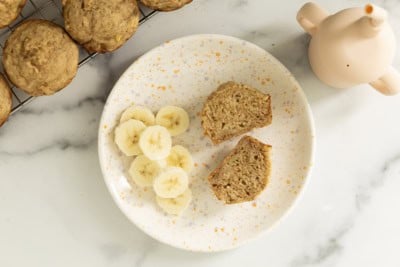 Egg free banana muffins on plate with banana slices.