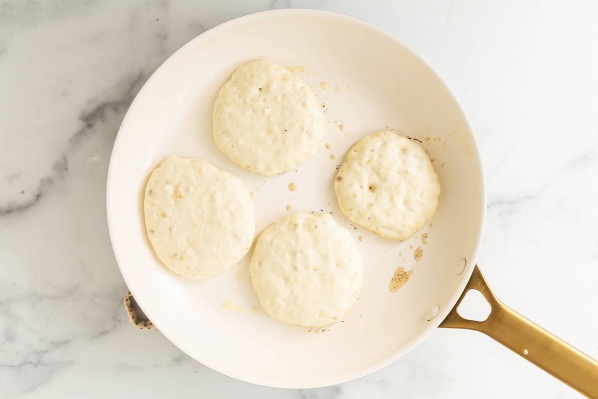 Eggless banana pancake batter cooking in a skillet.