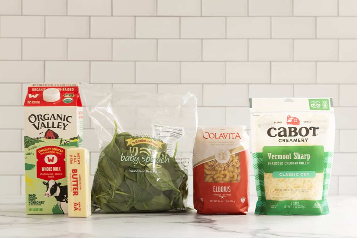 Milk, butter, spinach, pasta, and shredded cheddar cheese for green mac and cheese.