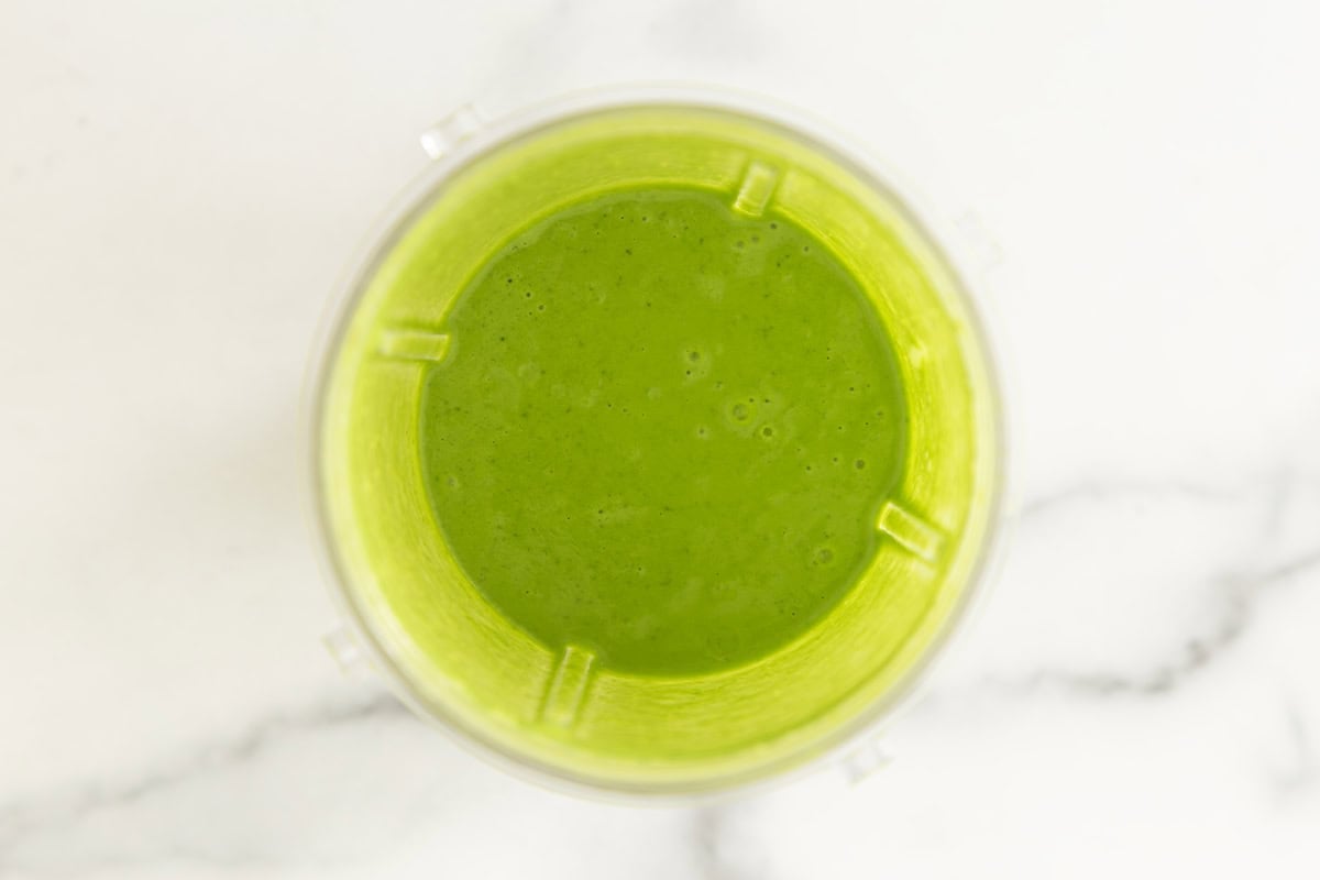Blended spinach and cheese sauce in a blender cup.