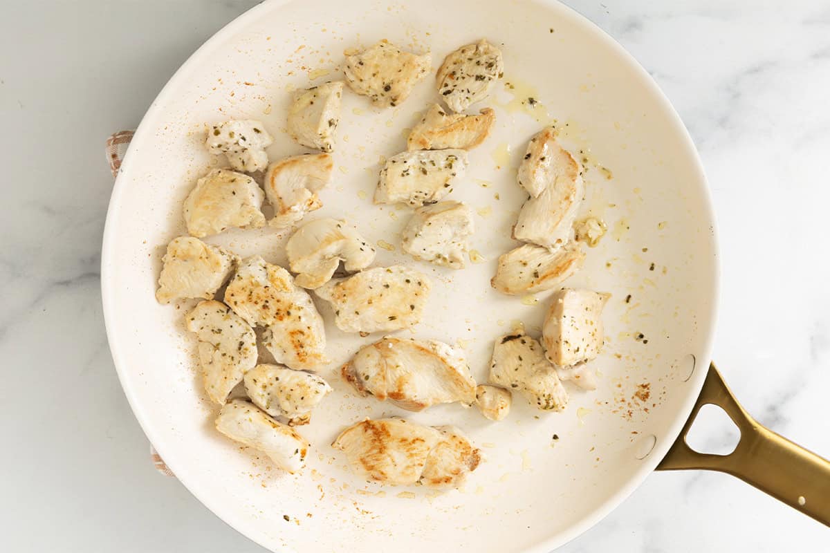 Frying chicken in pan for lemon orzo chicken.