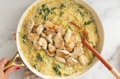 Lemon orzo chicken in pan with red spoon.