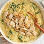 Lemon orzo chicken in pan with red spoon and orzo bag on side.