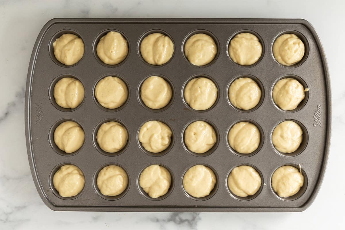 Vanilla muffin batter portioned into a mini muffin pan.